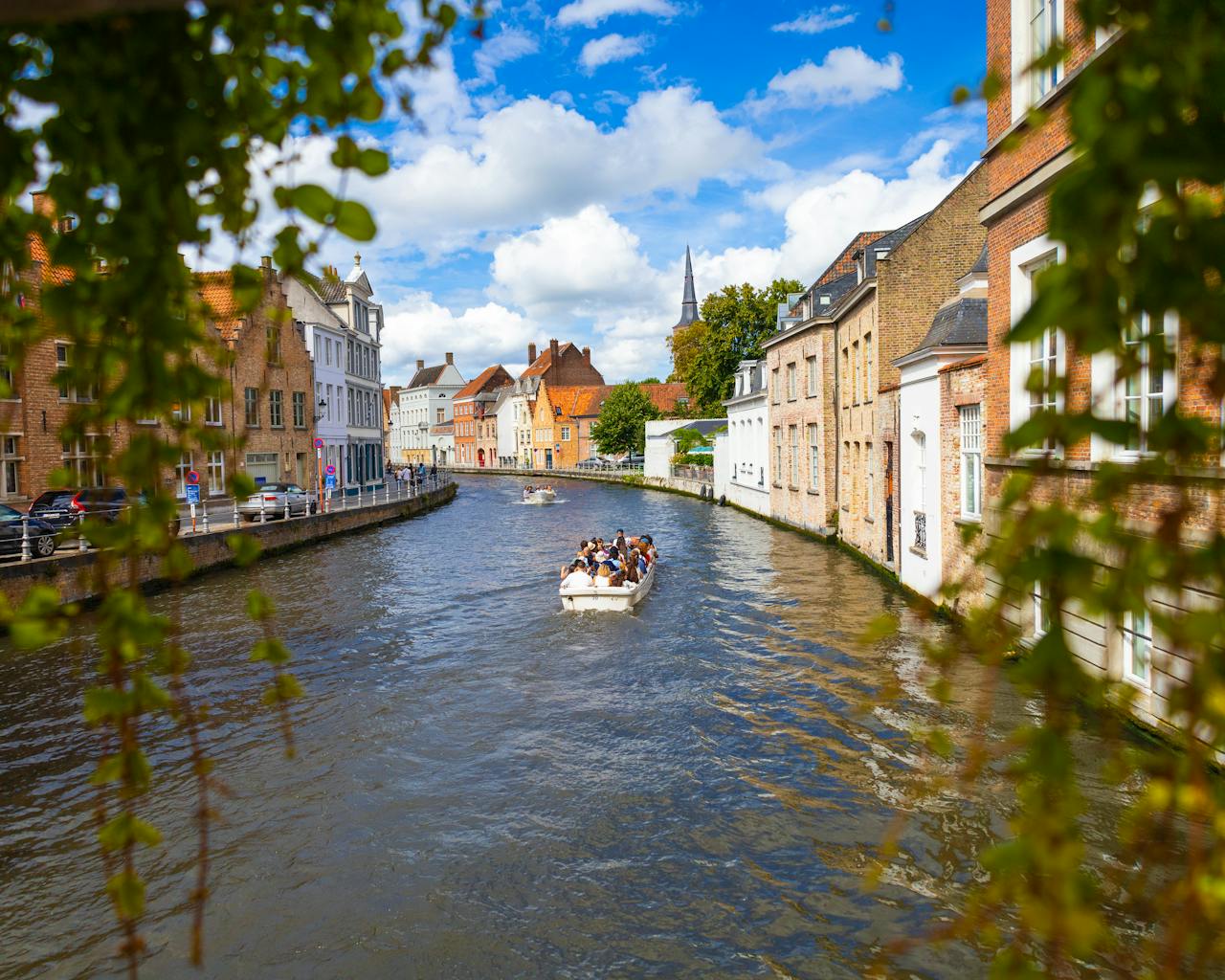 Explore the picturesque canals of Bruges, Belgium, with charming architecture and lush greenery.