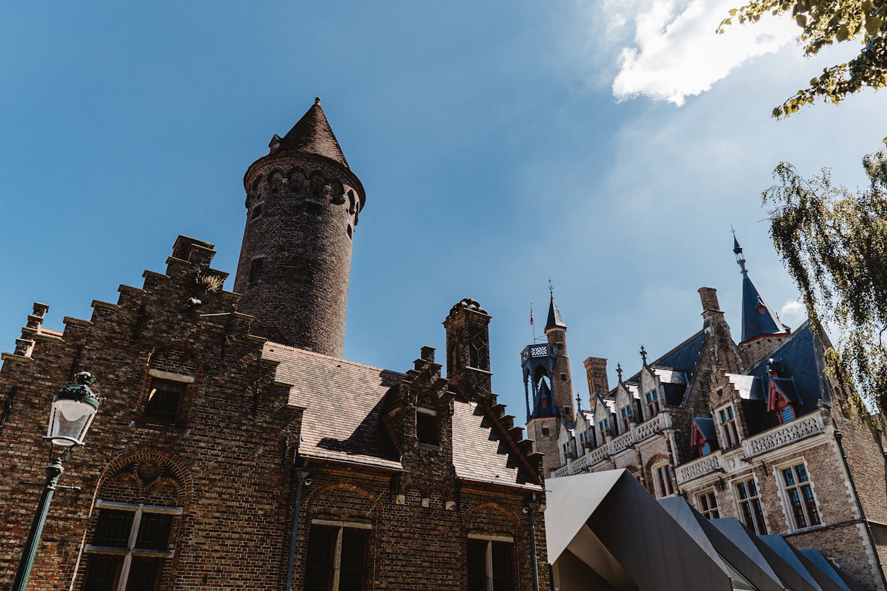 Charming medieval buildings and tower under clear sky in Bruges, Belgium.