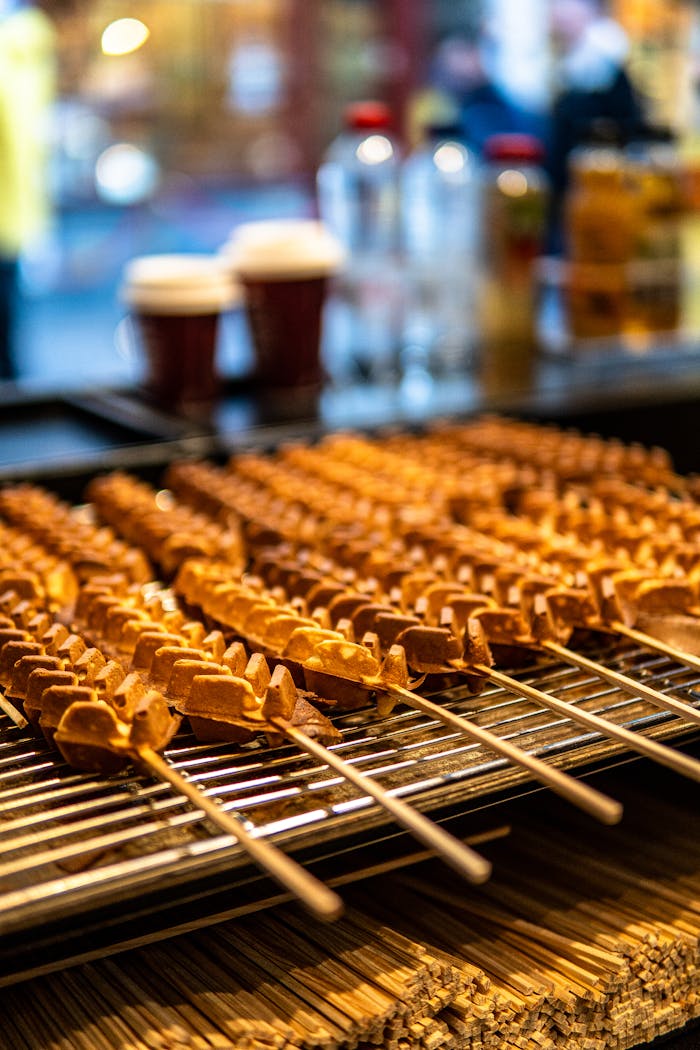 Close-up of skewered waffles at a vibrant Brugge street market in Belgium, highlighting local flavors.